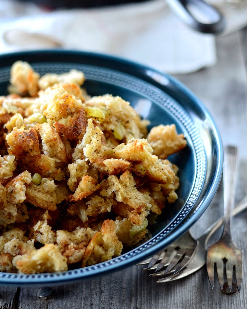 A blue bowl of simple sage stuffing with vintage forks next to it. 