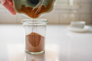 Pouring the homemade pumpkin pie spice into a small jar.