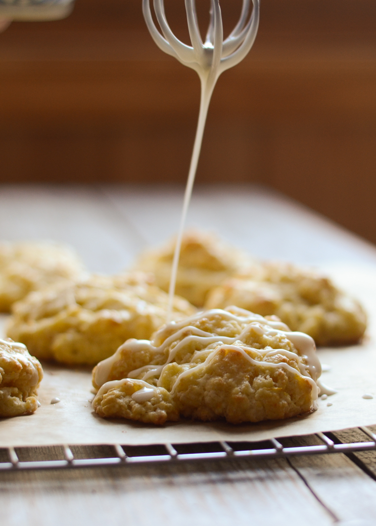 Drizzling the orange scones with the sweet glaze.