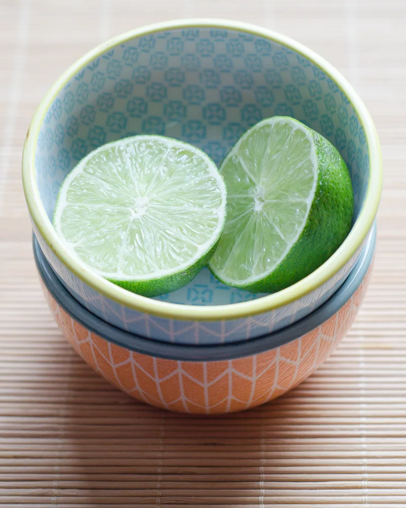 A lime cut in half in a pretty bowl, ready to be squeezed!