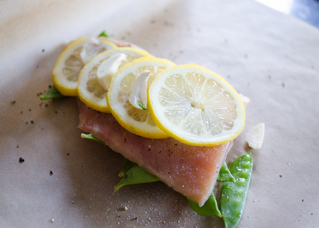 Placing all of the ingredients on a sheet of parchment paper to make salmon en papillote.