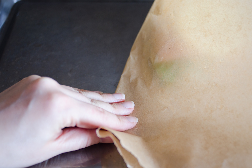 Creasing the piece of parchment paper on the baking sheet.