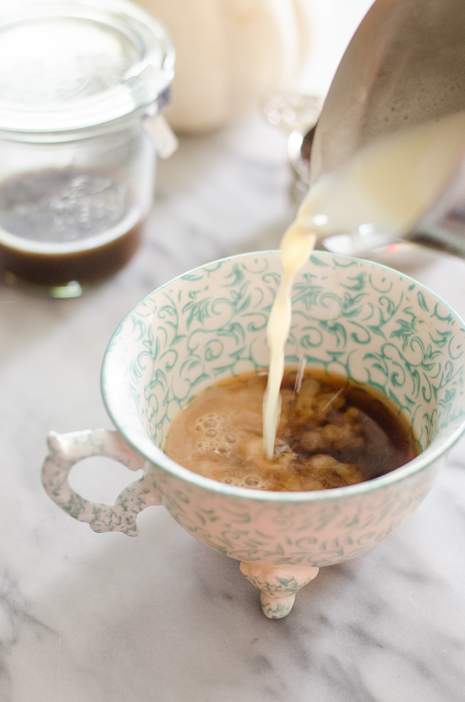 Pouring frothed milk on top of tea.