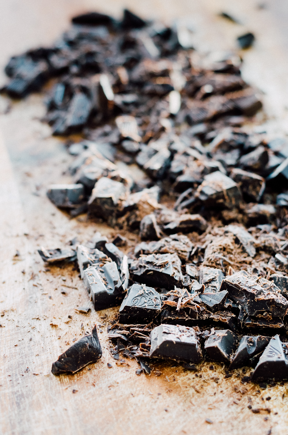 Roughly chopped chocolate on a wooden cutting board.