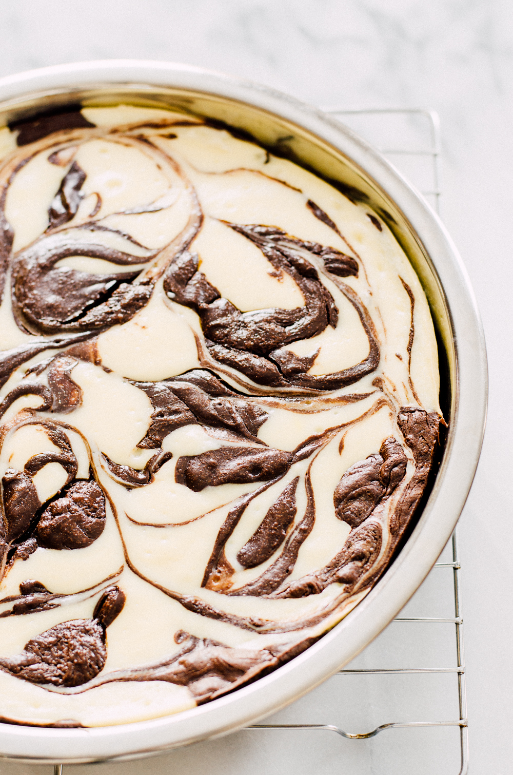 The finished pan of flourless chocolate swirl cheesecake cooling on a wire cooling rack.