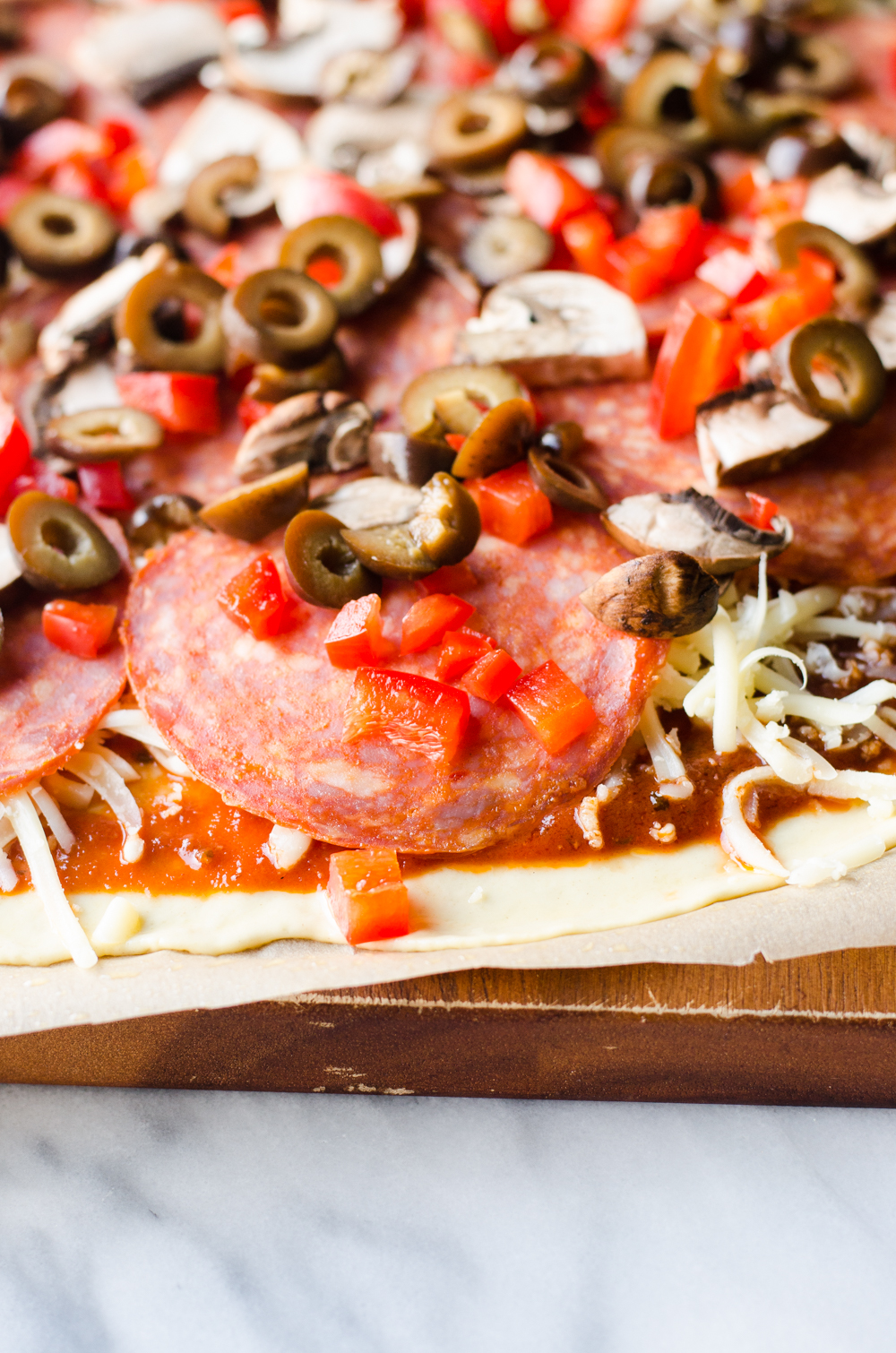 Homemade pizza on a wooden cutting board waiting to be baked!