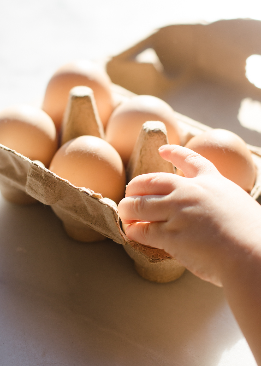 A little hand taking an egg out of a carton. 