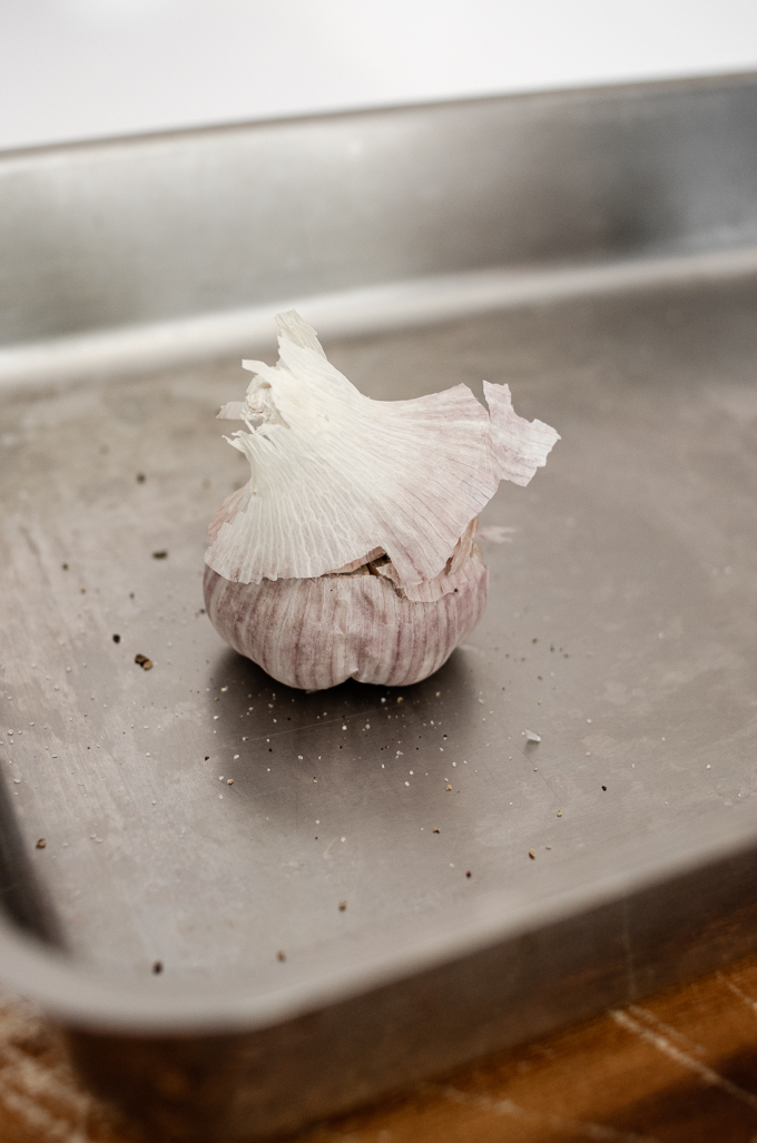 A head of garlic on a baking pan.
