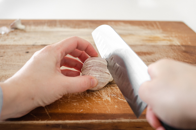 Slicing the top off a head of garlic.