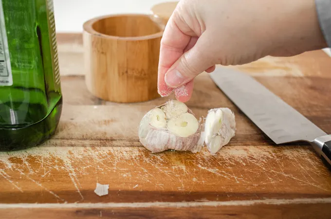 Sprinkling salt on the head of garlic before roasting it.