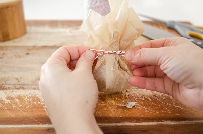 Tying bakers twine around the parchment paper packet.