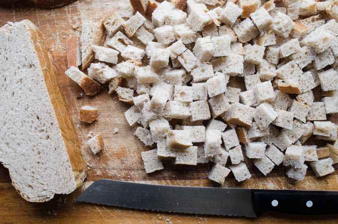 Sourdough bread on a cutting board cut into cubes.