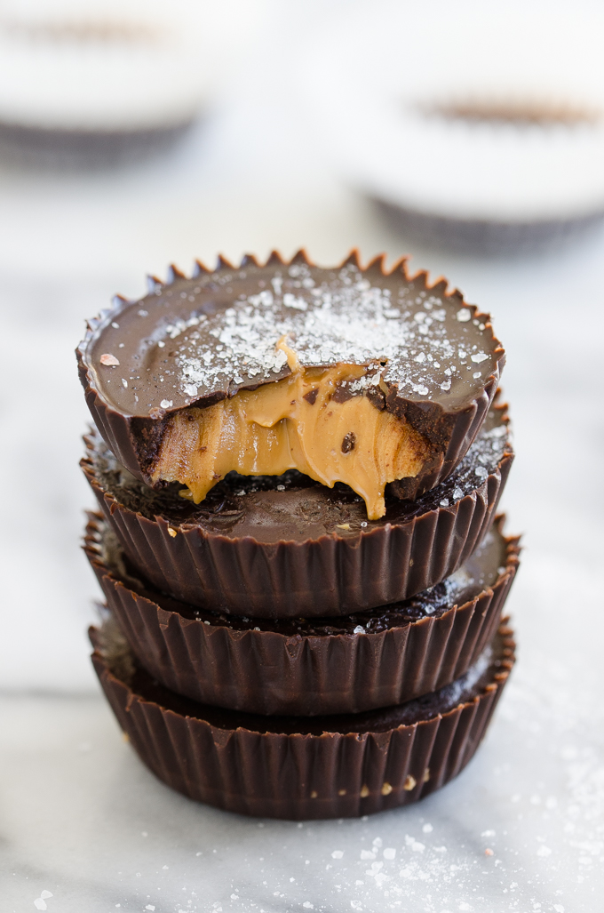 Dark chocolate peanut butter cups stacked on top of each other with a bite taken out of the top one.