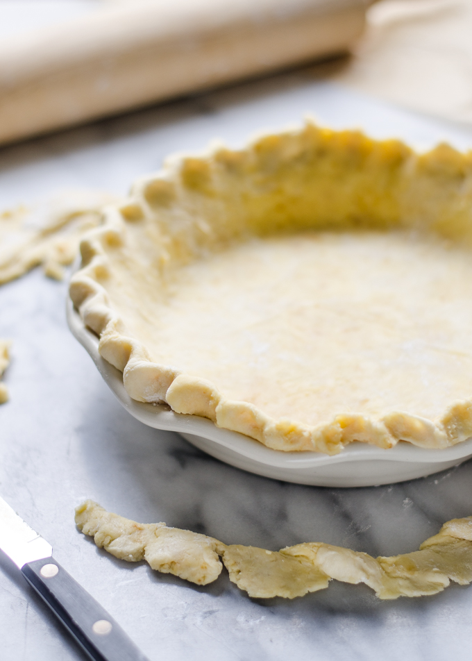 Sourdough Pie Crust in a pie pan with the crust trimmings around it.