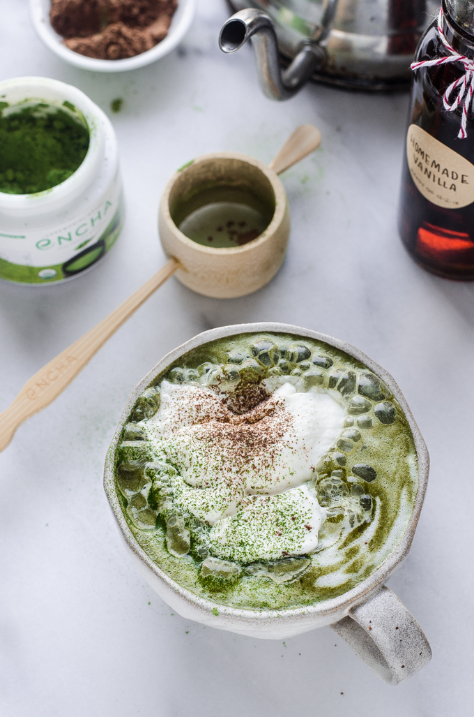 A mug of matcha cocoa with a tea kettle in the background.