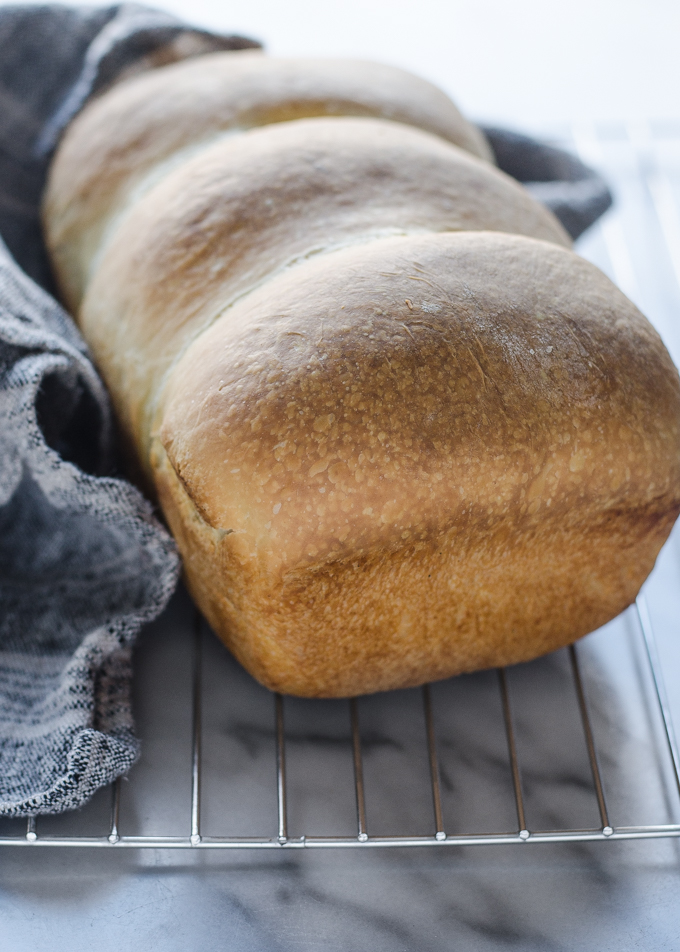 Soft sourdough sandwich bread cooling on a wire rack.