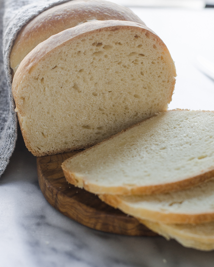 Slices of the bread on a small wooden cutting board with the loaf in the background.