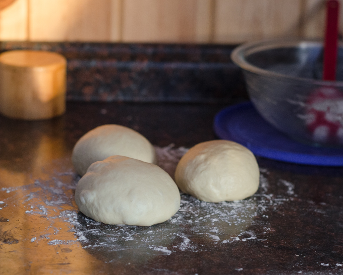 Three pieces of sourdough sandwich bread dough on a counter. 