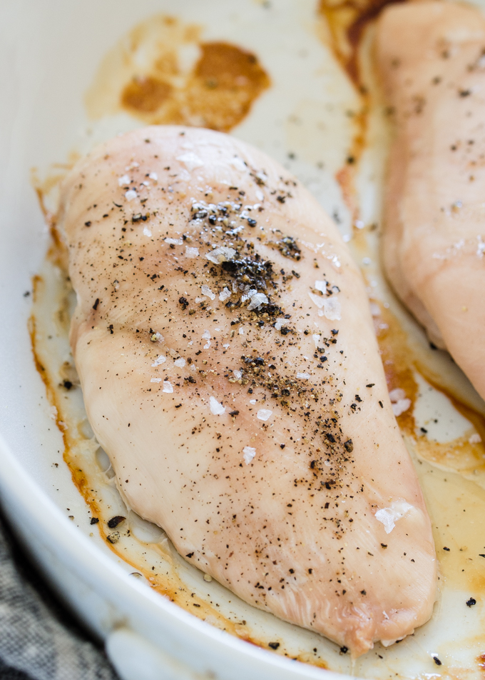 A close-up shot of a baked boneless skinless chicken breast with salt and pepper on top.