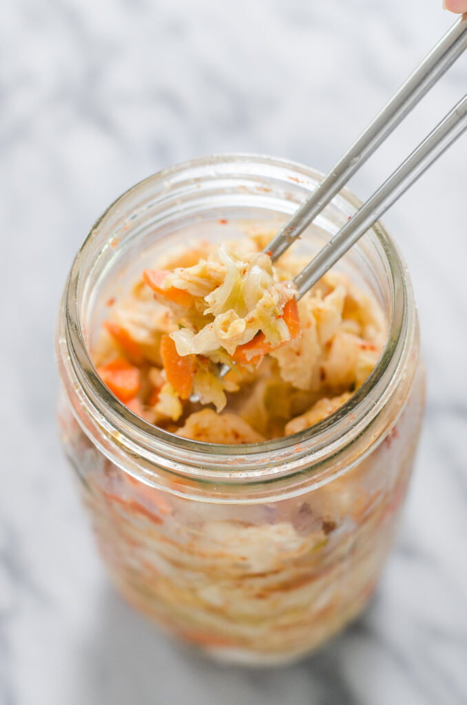 Homemade Kimchi in a bowl on a marble surface.