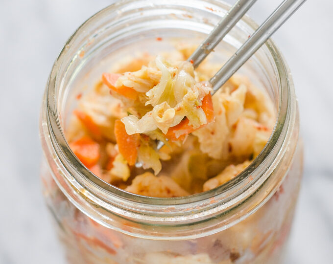 Homemade Kimchi in a bowl on a marble surface.