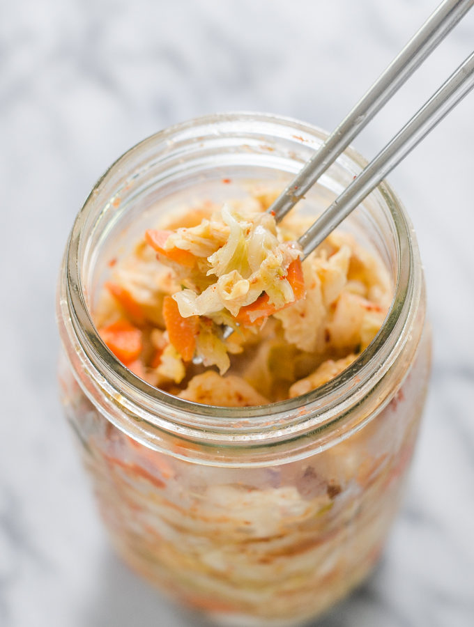 Homemade Kimchi in a bowl on a marble surface.