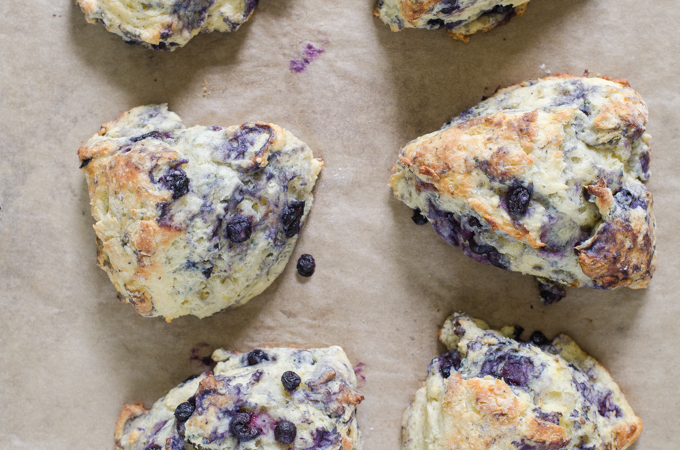 Blueberry scones fresh from the oven on a parchment-lined baking sheet.