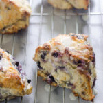 Blueberry Scones on a cooling rack drizzled with a Greek yogurt lemon glaze.