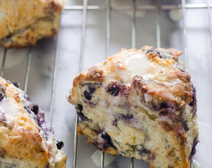 Blueberry Scones on a cooling rack drizzled with a Greek yogurt lemon glaze.