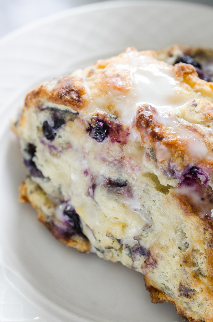 Close up shot of a blueberry scone drizzled with lemon-yogurt glaze.