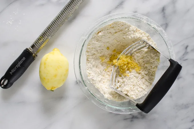 Cutting butter and lemon zest into the dry ingredients with a microplane zester off to the side.