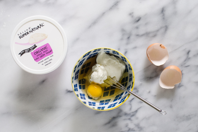 Greek yogurt, maple syrup, and and egg in a small blue bowl.