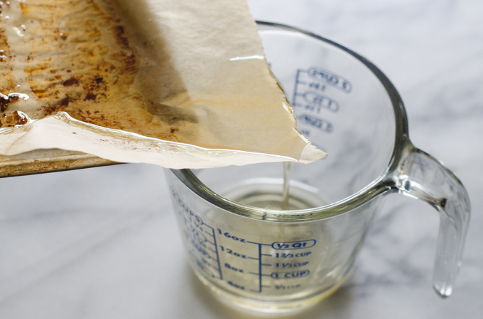 Pouring bacon grease into a measuring cup.