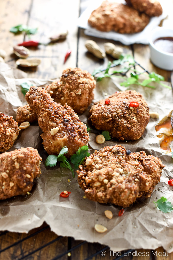 Pieces of fried peanut chicken on a piece of parchment paper.