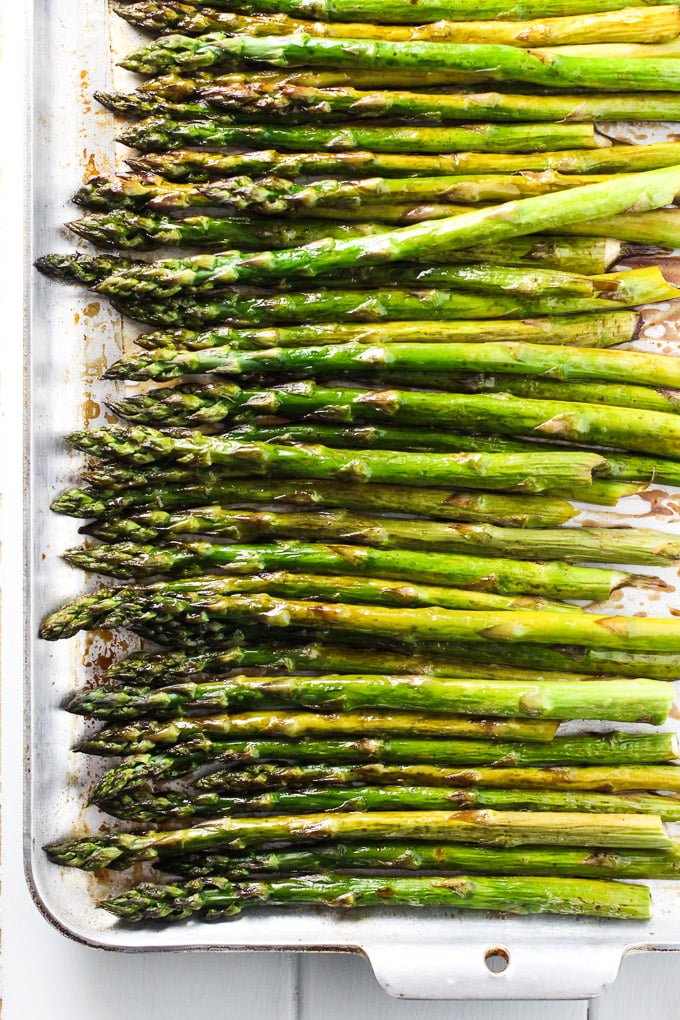 From above view of roasted asparagus on a baking tray.