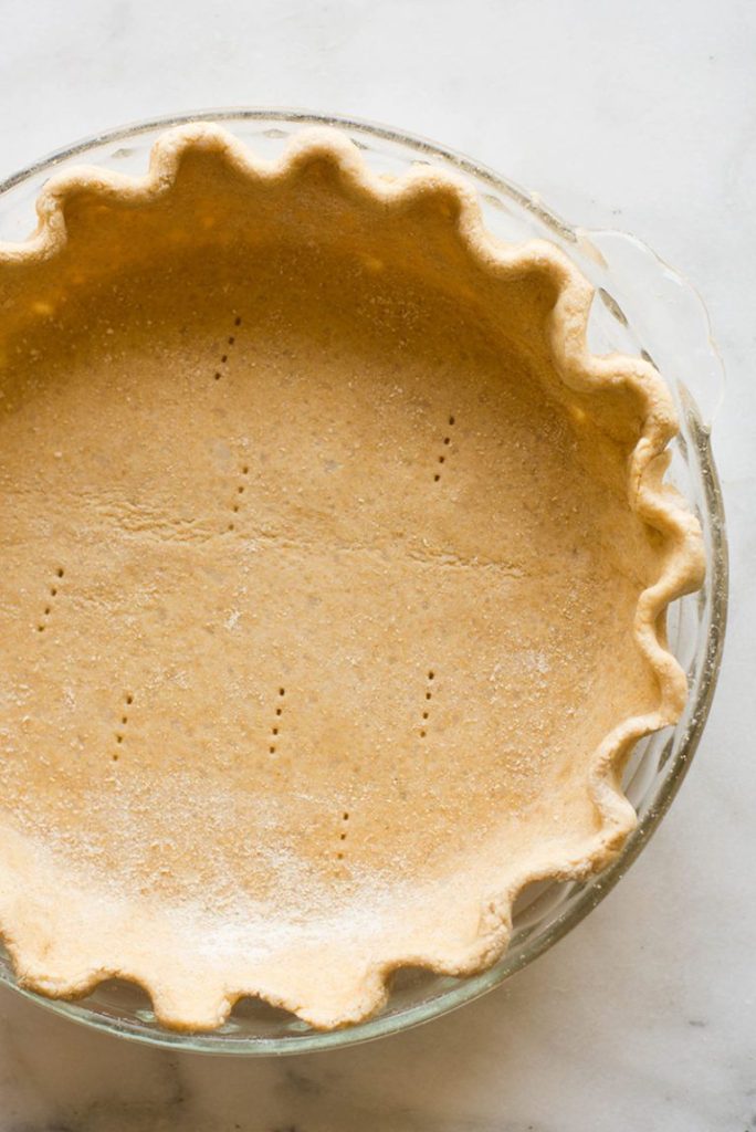 From above view of an unbaked pie crust, crimped, in a pie pan.