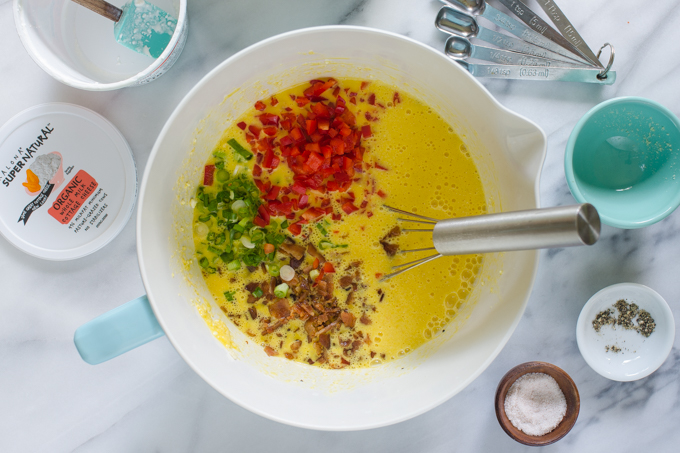 Bacon, green onions, and red bell peppers in the mixing bowl with the egg mixture.