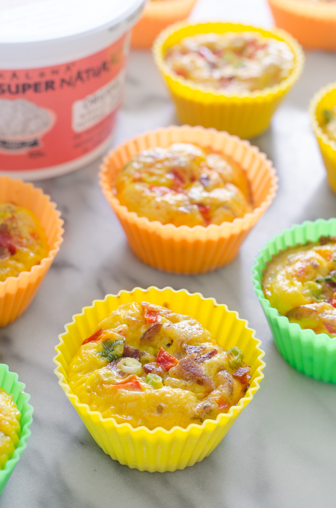 Several egg muffins on a marble surface with Kalona SuperNatural cottage cheese in the background.