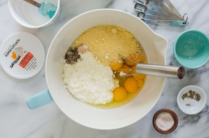 Eggs, parmesan cheese, cottage cheese, salt, and pepper in a mixing bowl with a whisk.