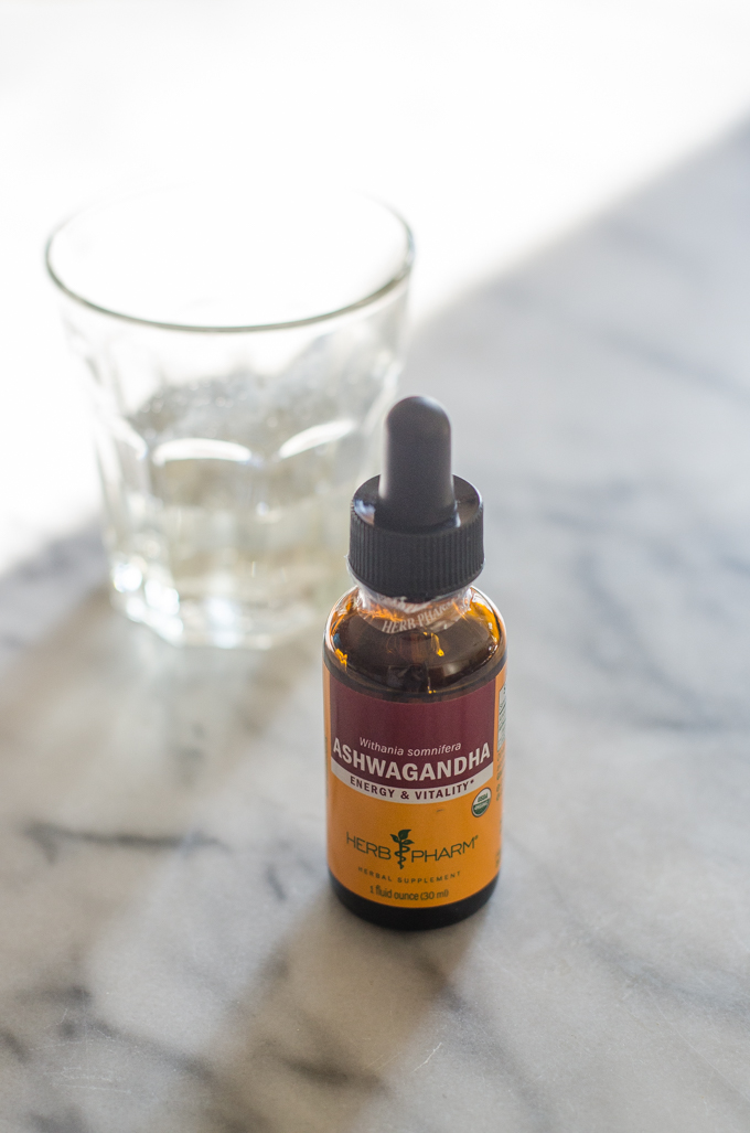 Ashwagandha tincture on a marble surface with a cup in the background.