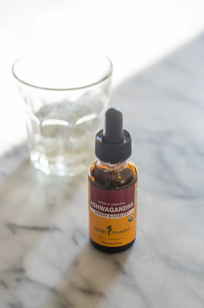 Ashwagandha tincture on a marble surface with a cup in the background.