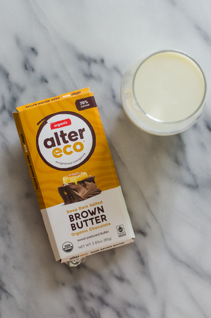 A chocolate bar in its wrapping next to a glass of milk.