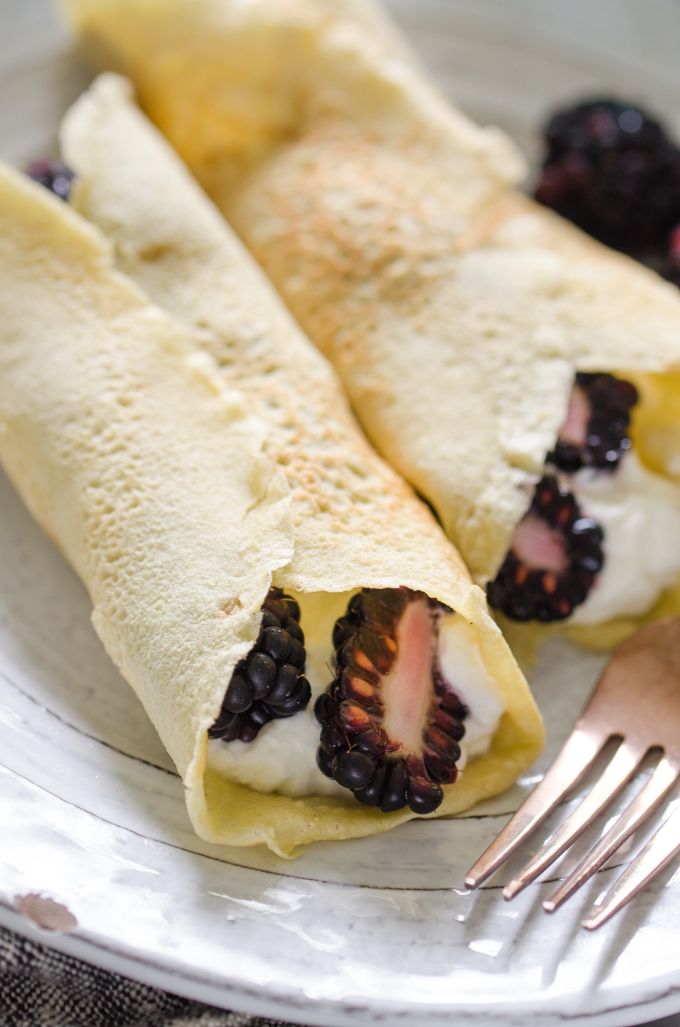 Close up shot of KETO crepes filled with whipped cream and blackberries.