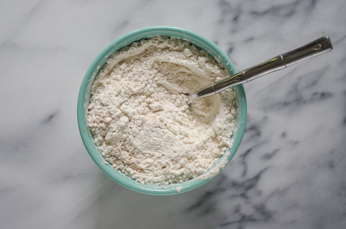 Dry ingredients for the banana bread in a bowl on a marble surface.