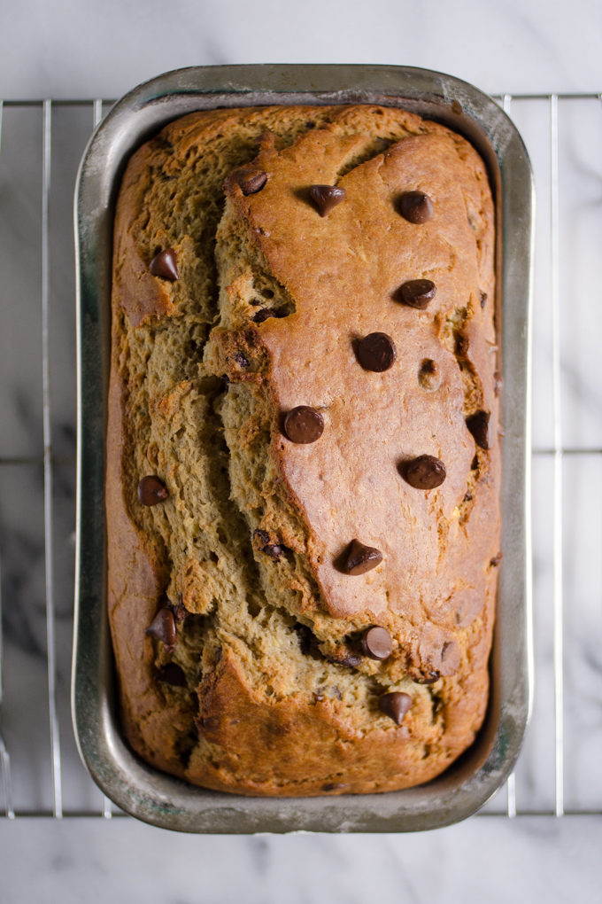 Sourdough banana bread in loaf pan on a cooling rack on a marble surface.