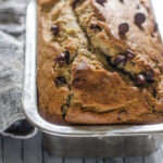 Sourdough banana bread in loaf pan on a cooling rack on a marble surface.