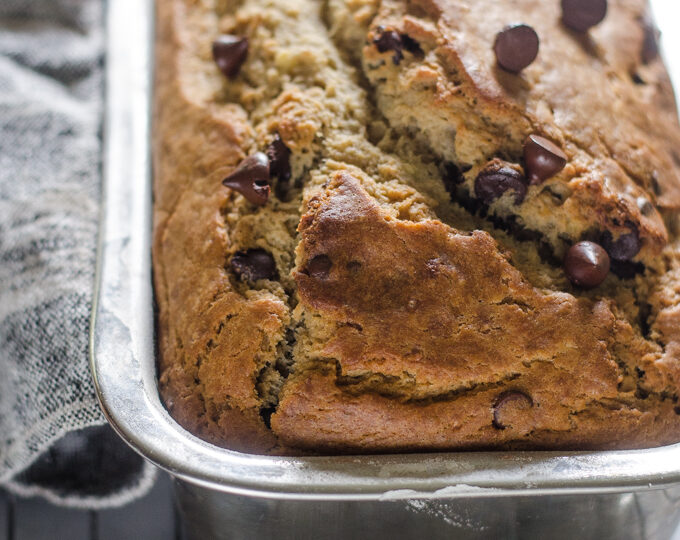 Sourdough banana bread in loaf pan on a cooling rack on a marble surface.