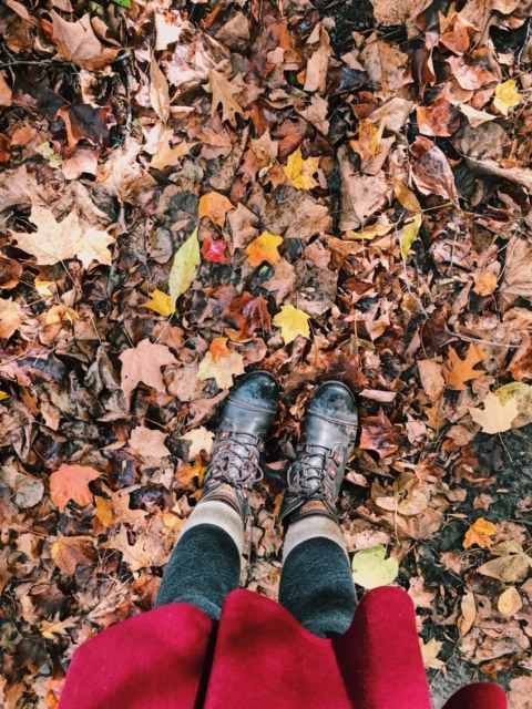 Photo of fallen leaves with feet in the picture.