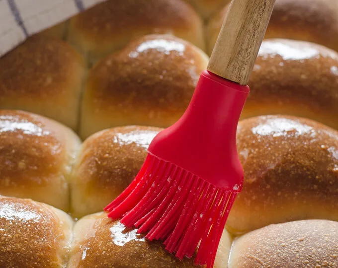 Brushing Sourdough Pull Apart Rolls with melted butter.