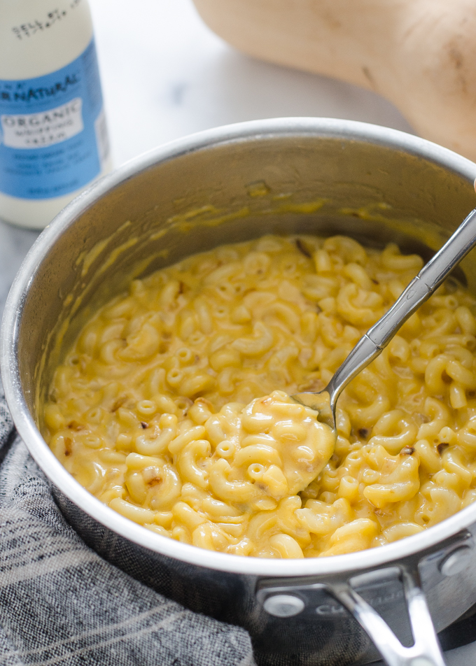 A spoonful of butternut squash mac and cheese held over the pot.